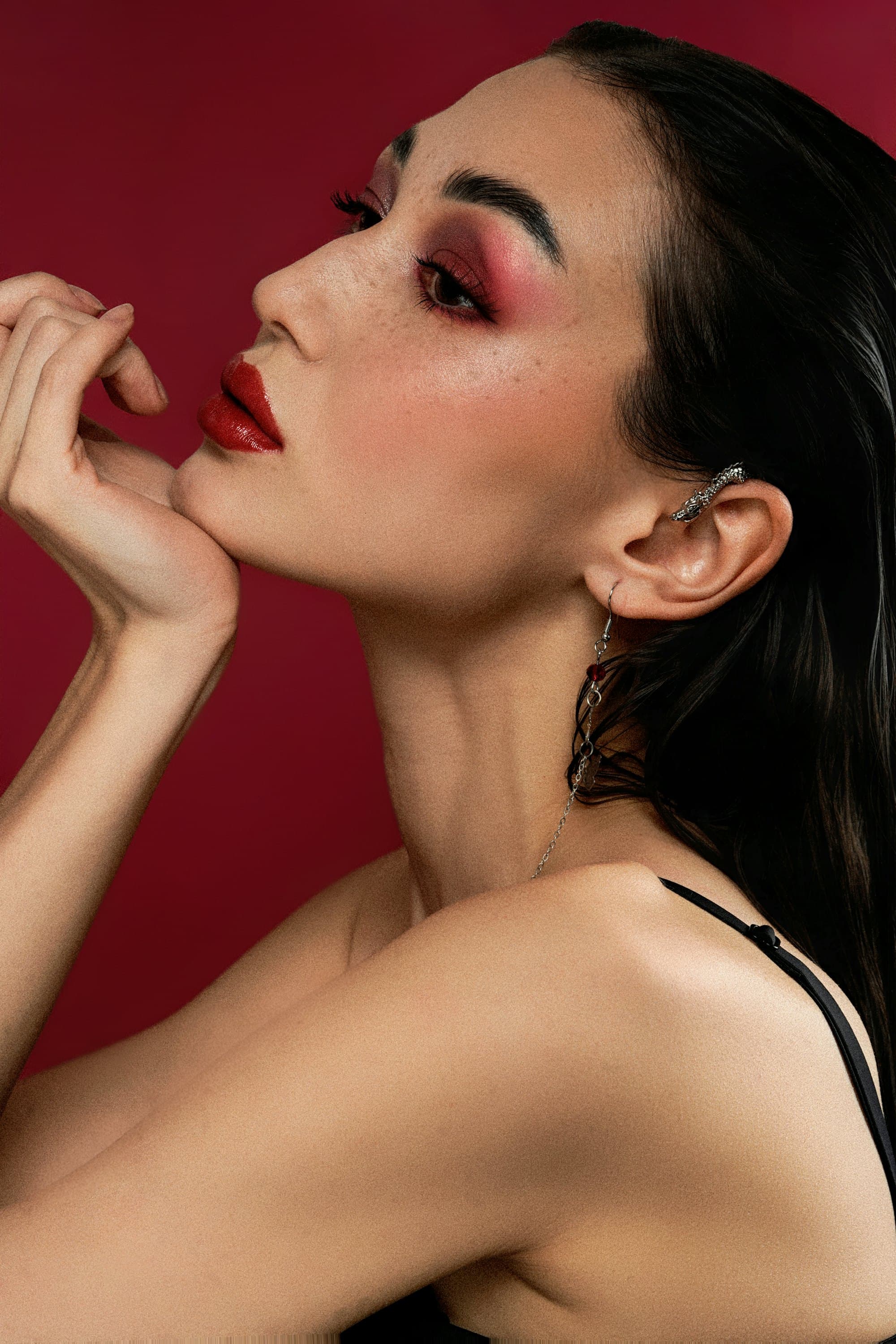 Close-up editorial beauty portrait with sculpted eye makeup and a statement earring